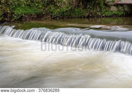 Long Exposure Of A Watefall On The River Lim Walkway At Lyme Regis In Dorset.