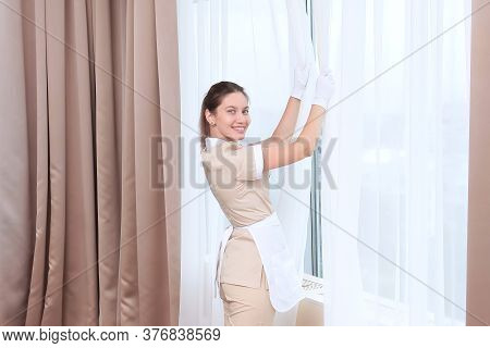 A Maid In White Gloves And Uniform Smiles And Airs The Room In A Hotel Room Or Apartment. The Concep
