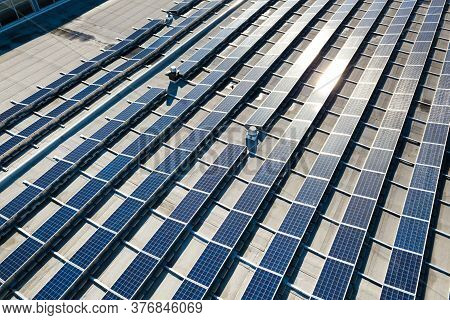Aerial View Of Many Photo Voltaic Solar Panels Mounted Of Industrial Building Roof.