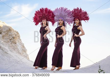 Three Young Women Pose Against A Blue Sky On A Cliff