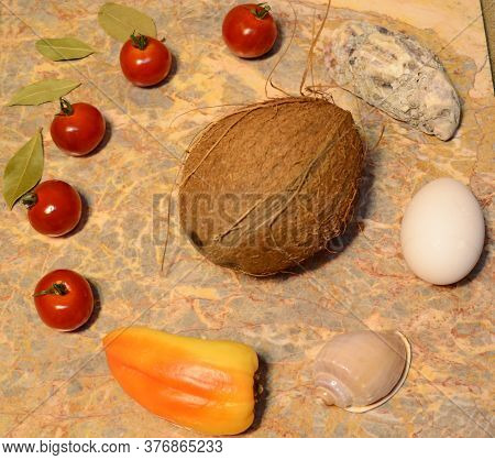 Vegetables, Seashells, Egg And Coconut On A Marble Surface: Cherry Tomatoes, Bell Peppers, Bay Leave