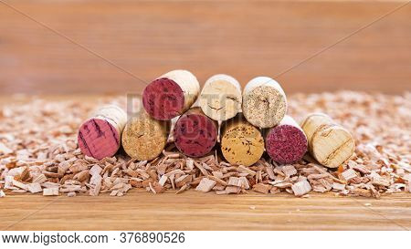 Corks With Red Stain Lie In A Stack On Background From Wood Chips. Natural Wood Fon With Heap Of Cor