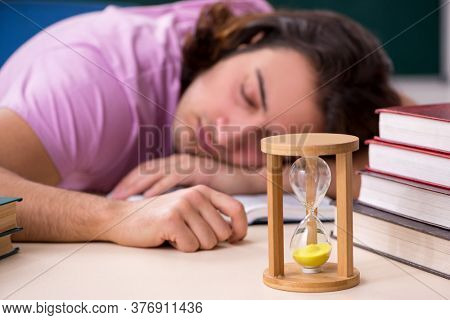 Young male student in the classroom at time management concept