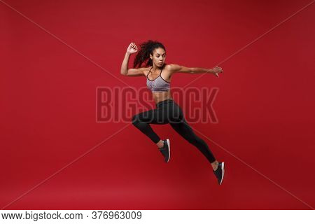 Side View Of Young African American Fitness Woman In Sportswear Posing Working Out Isolated On Red W