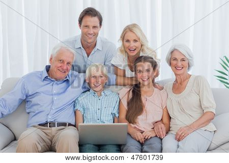 Genişletilmiş aile kanepede oturan ve bir dizüstü bilgisayar kullanarak