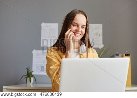 Smiling Satisfied Female Freelancer Working On Laptop And Talking On Smart Phone, Expressing Positiv