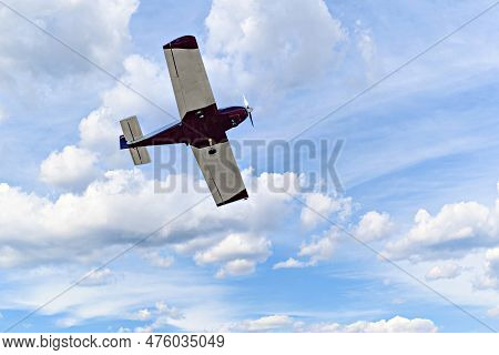 Single Engine Ultralight Plane Flying In The Blue Sky With White Clouds