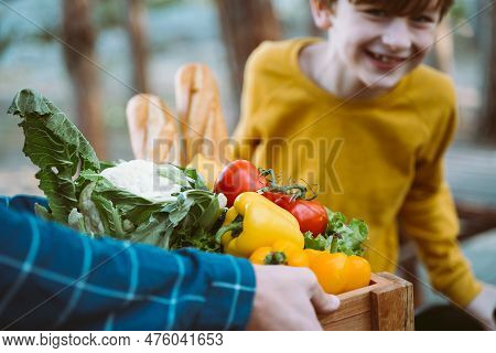 Father And Son Farmers Holding A Wooden Crate With Supplies Groceries. Man Male Dad And His Should K