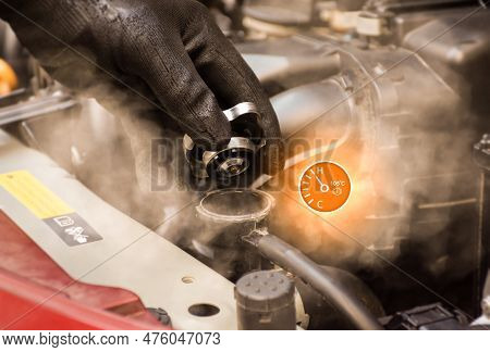Auto Mechanic Hand Opens The Radiator Cap With Steam Escaping Around The Engine Compartment From The