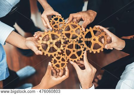 Office Worker Holding Cog Wheel As Unity And Teamwork In Corporate Workplace Concept. Diverse Collea
