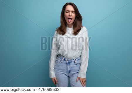 Funny Young Brunette Woman In Shirt With Grimace On Studio Background