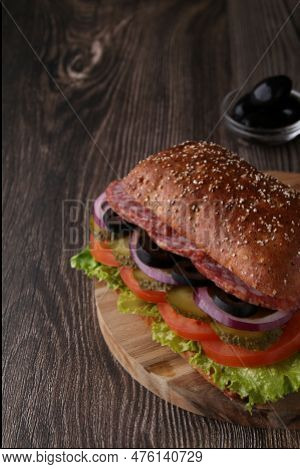 Photo Sandwich With Layers Of Sausage And Vegetables On A Dark Background