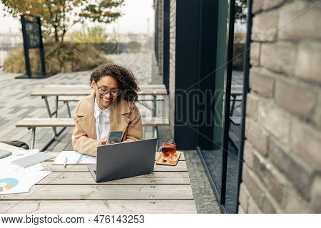 Afro American Woman Freelancer Working Remotely While Sittiing On Cafe Terrace