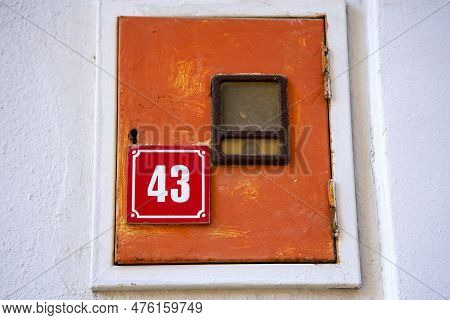A Red House Number Plate Showing The Number 43. A Small Built-in Cupboard.