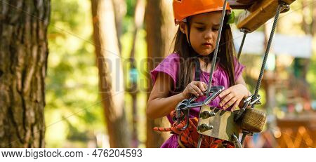 Little Brave Caucasian Girl Treerunner Fasten The Carabiner Clip Before Climbing At Outdoor Treetop 