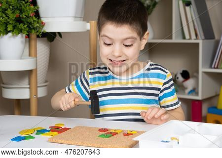 A Preschool Child Plays With A Mosaic, Builds Figures On A Board, Hammering Nails With A Hammer On M
