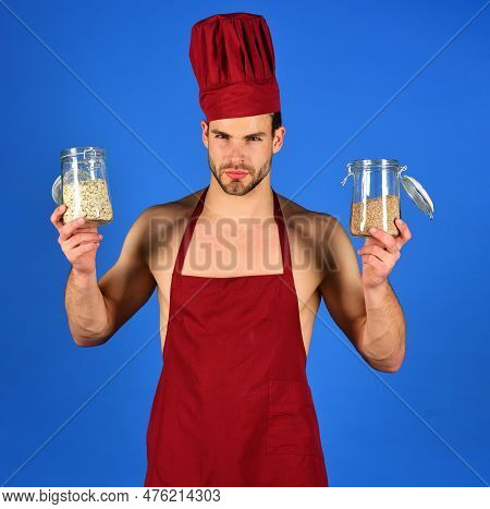 Professional Male Cook In Chef Hat And Apron Holds Glass Jars With Groats And Cereals. Breakfast And