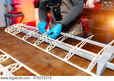 Close-up Image Of Young Male Engineer Or Technician Working On Drone Details In Lab. Plane Wing.