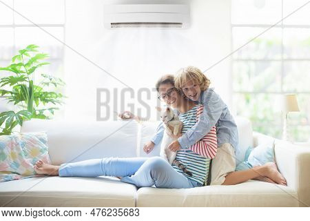 Mother And Child With Air Conditioner Remote