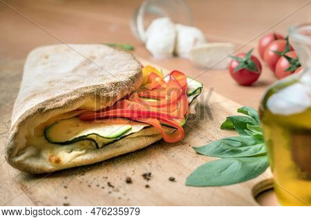 Italian Food, Closed Calzone Pizza On Rustic Wooden Background. Filled With Peppers And Zucchini. On