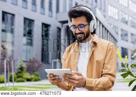 A Young Inus Man Walks Around The City In Headphones, A Businessman In A Shirt Watches An Online Vid