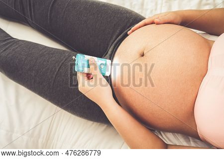 Pregnant Woman Feeling Happy At Home While Taking Care Of Her Child. The Young Expecting Mother Hold