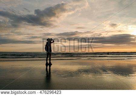 Silhouette Of A Woman On The Beach Enjoying The Sunset At Seminyak Beach.