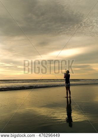 Silhouette Of A Woman On The Beach Enjoying The Sunset At Seminyak Beach.