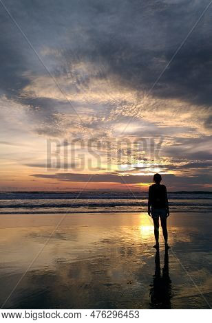 Silhouette Of A Woman On The Beach Enjoying The Sunset At Seminyak Beach.