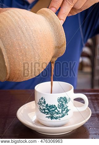 Man Pouring Coffee From Claypot. Close Up View.