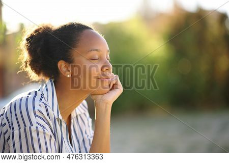 Black Relaxed Woman Resting Alone In A Park At Sunset