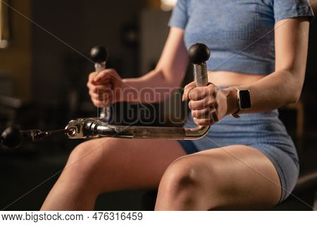 Strong Woman Sitting While Rowing At The Cable Machine For Back Muscles, Intense Workout At The Gym.