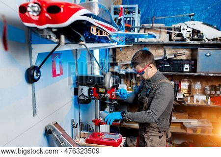 Young Male Engineer Or Technician Using Drill For Drone Details In Lab. Aircraft Capable Of Gps Surv