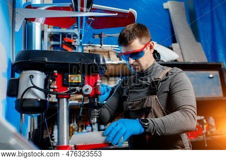 Young Male Engineer Or Technician Using Drill For Drone Details In Lab. Aircraft Capable Of Gps Surv