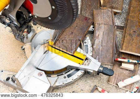 Close-up Top-down View Of A Professional Circular Saw With A Pile Of Laminate Flooring Offcuts.