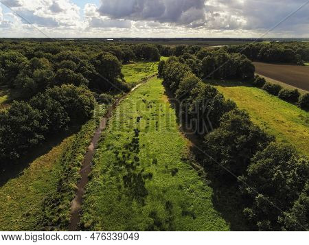 Aerial View Of A Stream Through The Meadow Surrounded By A Lot Of Forest Somewhere In The Netherland