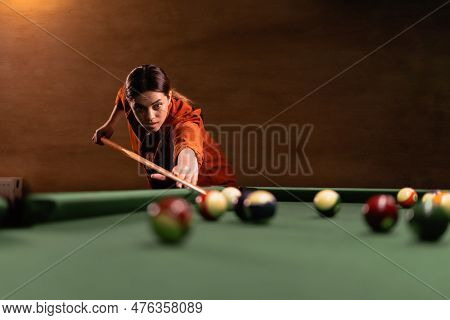 Womans Hand With Cue Pointing At Billiard Ball At Table