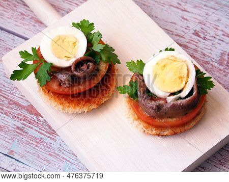 Toasts With Tomato, Egg And Anchovy On A White Serving Board. View From Above.