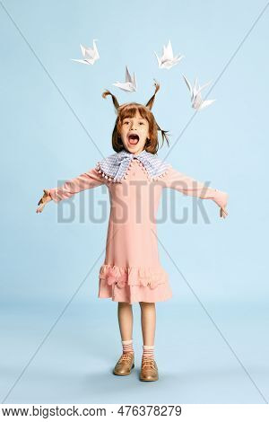 Full-length Portrait Of Happy Little Girl, Child In Pink Dress Posing Against Blue Studio Background