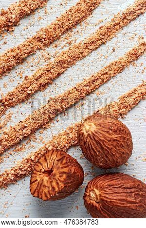 Three Whole Nutmegs And Half Against Grated Coca Tracks Made From Grated Nutmeg Powder. Top View Wit