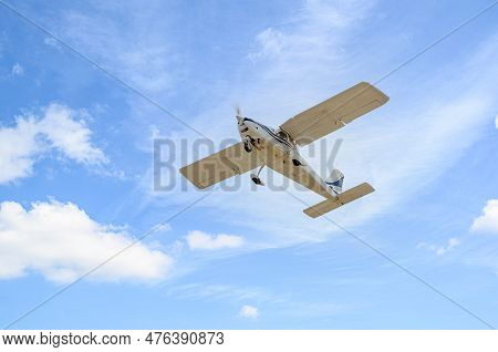 Single Engine Ultralight Plane Flying In The Blue Sky With White Clouds