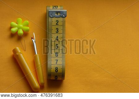 Needle Threader For The Visually Impaired, Measuring Tape And Ripper On Yellow Fabric, Sewing Tools