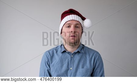 The Sad And Sorrowful European Young Man In A New Years Hat Looks Gloomily Into The Camera. Disappoi