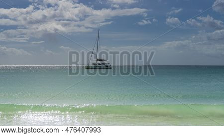 A White Yacht Is Sailing In A Calm Boundless Turquoise Ocean. The Sun Glare On The Water. Clouds In 