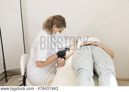 Female Specialist Doing Hair Removal Procedure With Electrolysis On Hand Of White Young Client, Elec