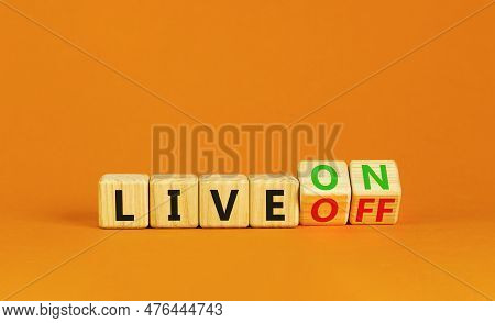Live On Or Off Symbol. Businessman Turns Wooden Cubes And Changes Word Live Off To Live On. Beautifu