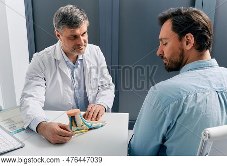 Flat Feet Treatment. Podiatrist Doctor Consulting Adult Man With Flatfoot, Explaining Treatment Meth