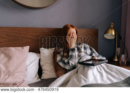 Depressed Grief-stricken Young Woman Lying On Bed Covering Face With Hand And Crying While Holding P