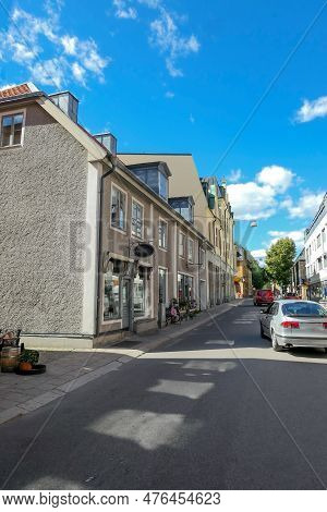 Cars Driving On Street Admist Buildings During Summer