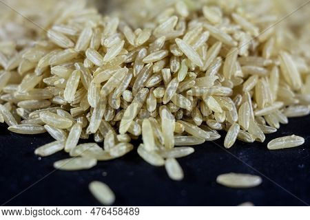 Studio Macro Shot Of A Pile Of Brown Rice, Also Called Complete, Integral Or Wholegrain Rice, With A